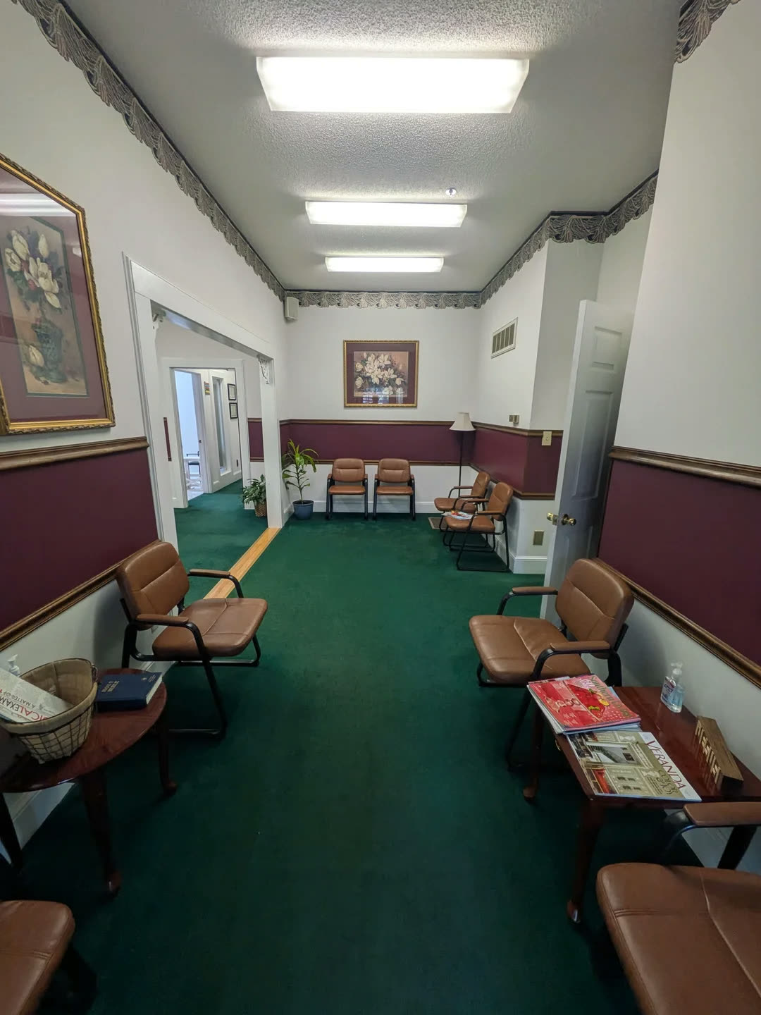 A 1990s office waiting room with green carpet, burgundy wainscoting and brown leather chairs